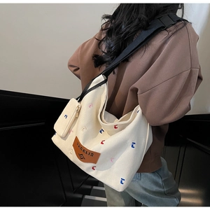 Detail of white canvas tote bag with colorful embroidery and mini zipper pouch pendant