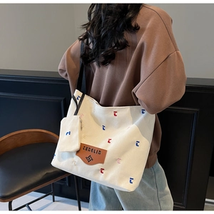 Detail of canvas tote bag with colorful embroidery, leather label and mini zip pouch