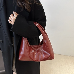 Minimalist deep red hobo bag with glossy finish and seamless handle for elegant winter styling