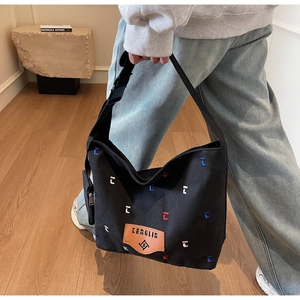 Detail of black canvas hobo bag with colorful embroidery and adjustable shoulder strap