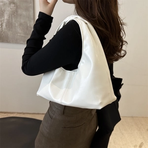 Minimalist white patent leather Hobo bag with glossy finish shown as an underarm shoulder bag