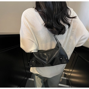 Detail of black PU leather shoulder bag with silver rivet studs and metallic eyelets