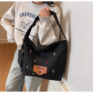 Close-up of black canvas tote bag with colorful embroidery and adjustable strap buckles