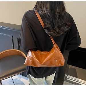 Close-up of caramel hobo shoulder bag featuring vintage studs and oil wax leather texture