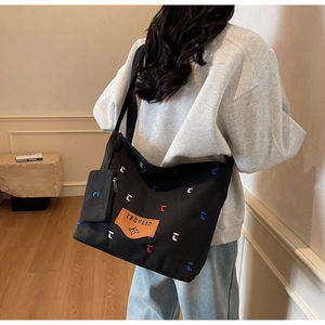 Detail of black canvas tote bag with colorful embroidery and matching mini pouch