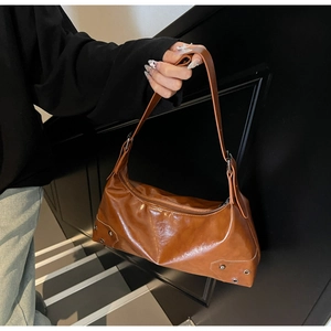 Detail view of brown glossy oil-wax leather shoulder bag with vintage rivet accents