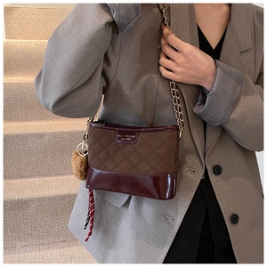 Détail du sac seau bandoulière avec surpiqûres, chaîne dorée et pendentif peluche