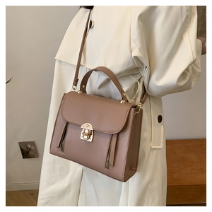 Detail of elegant dusty pink shoulder bag featuring gold twist lock and metal zippers
