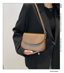 Brown leather crossbody bag with flap cover shown on model wearing black blazer suit
