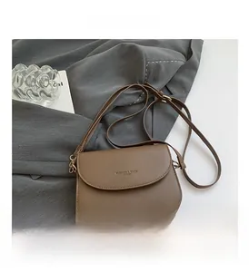 Detail view of mocha brown leather crossbody bag with gold buckle and adjustable strap