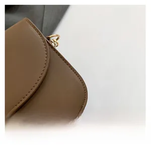 Macro detail of brown leather texture with neat stitching and golden metal D-ring on bag