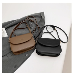 Detail of minimalist brown and black saddle bags with elegant gold hardware accents