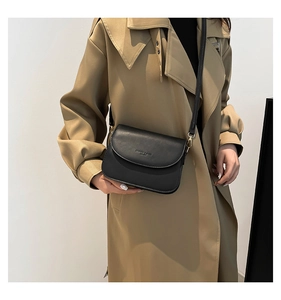 Detail of a matte black saddle bag with fine leather texture and golden metal hardware