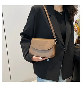 Close-up of a brown leather saddle bag styled with a black blazer for a chic casual look
