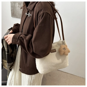 Detail of cream plush tote bag featuring dark brown leather straps and star charm