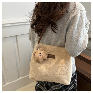 Détail du sac seau en fausse fourrure beige avec écusson en cuir et breloque ourson