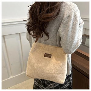 Détail d'un sac cabas en fausse fourrure beige avec un écusson en cuir marron gravé