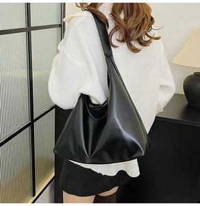 Detail of minimalist black leather tote bag showing soft texture and pleated design