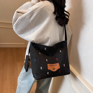 Large black canvas tote bag with embroidery and small coin purse shown on model