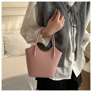 Pink PU leather bucket bag with top handles shown with a stylish casual outfit