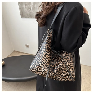 Detail of leopard print tote bag featuring a black decorative bow and leather straps
