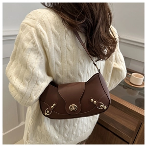 Detail of a brown vintage crescent bag featuring metallic rivets and a gold-tone clasp
