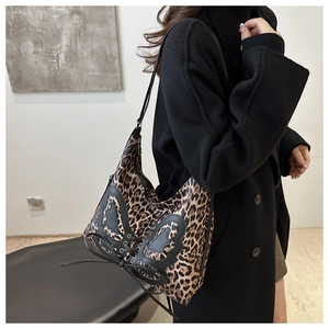 Detail of leopard print tote bag featuring black leather butterfly appliques and lace-up design