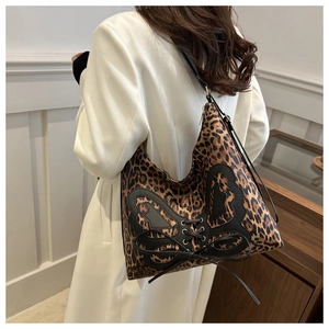 Side view of leopard print hobo bag featuring black butterfly patch and thin leather straps