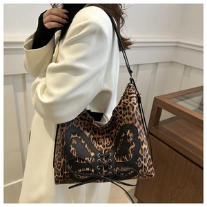 Detail of leopard print tote bag featuring a black leather butterfly patch and lacing
