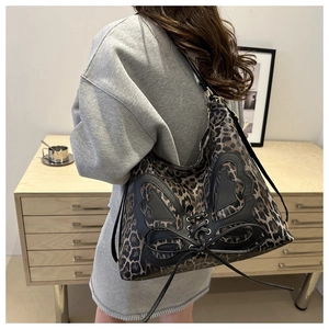 Detail of leopard print tote with black butterfly patchwork and lace-up strap details