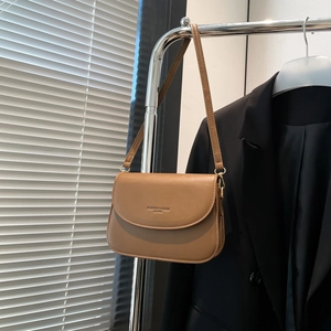 Minimalist tan leather crossbody bag on metal hanger with soft window light