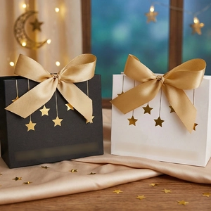 Nahaufnahme eleganter schwarz-weißer Geschenktüten mit Goldsternen und Satinschleifen