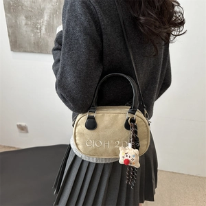 Minimalistische beige Umhängetasche mit Bärenanhänger getragen von Model im grauen Pulli