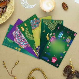 Detail of green and purple Hari Raya money envelopes with gold crescent and mandala patterns
