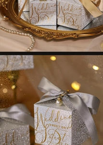 Macro shot of silver glitter wedding favor box with grey silk ribbon and pearl pendant charm