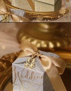 Macro detail of silver glitter wedding favor box with champagne ribbon and gold pendant