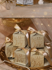 Close-up of golden shimmer wedding favor boxes with satin bows and pearl charms