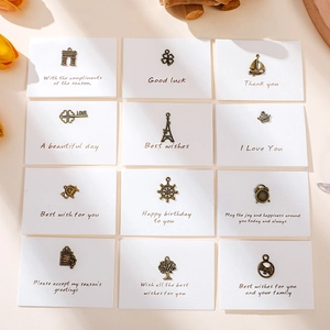 Detail of 12 vintage bronze pendants including Eiffel Tower and heart keys on gift cards