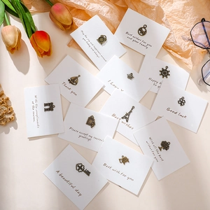 Detail of vintage bronze alloy charms on minimalist greeting cards with envelopes