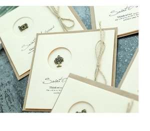 Detail of vintage kraft greeting cards with bronze metal charms and natural twine tie