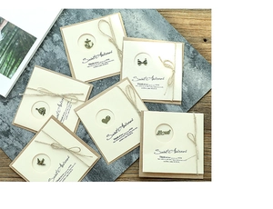 Detailed view of vintage kraft greeting cards with bronze metal charms and hemp rope ties