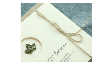 Close-up of vintage bronze crown pendant with natural jute twine on cream paper card