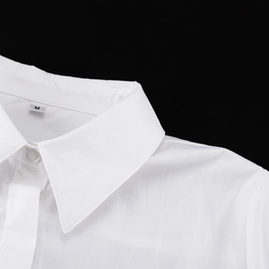 Primer plano de cuello de solapa blanco y botones con etiqueta de talla M en fondo negro
