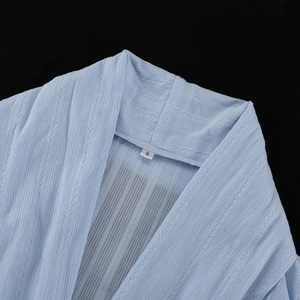 Détail d'un cardigan bleu clair en coton avec maille côtelée et dentelle ajourée délicate