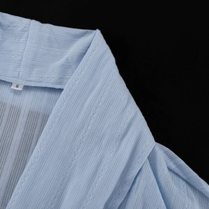 Détail du tissu en coton bleu clair avec rayures verticales et texture tricotée