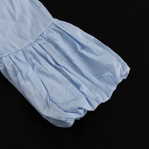 Détail de manche bouffante en coton bleu clair avec poignet élastique et texture jacquard
