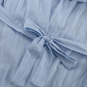 Détail du tissu en coton bleu clair avec dentelle ajourée et ceinture à nœud