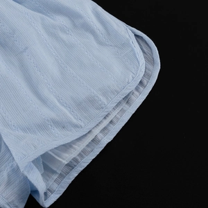 Détail du tissu en coton bleu clair avec textures verticales et broderie à jours échelle