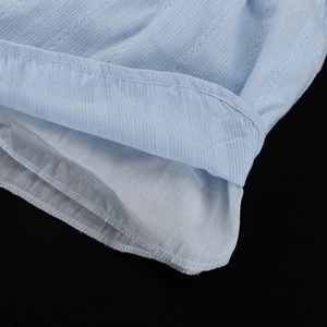 Détail du tissu en coton à rayures bleu clair avec tricot ajouré et ourlet cousu