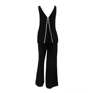 Detail van zwarte mouwloze top met V-hals en broek met witte contrasterende biezen